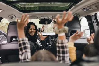 enfants et parents dans une voiture qui lèvent les bras
