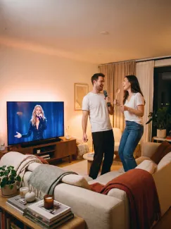 Photo réalisée avec l'IA qui représente un couple dans son salon en train de chanter devant Céline Dion à la télé