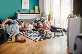 famille avec son chien faisant du gainage sur un tapis dans son salon